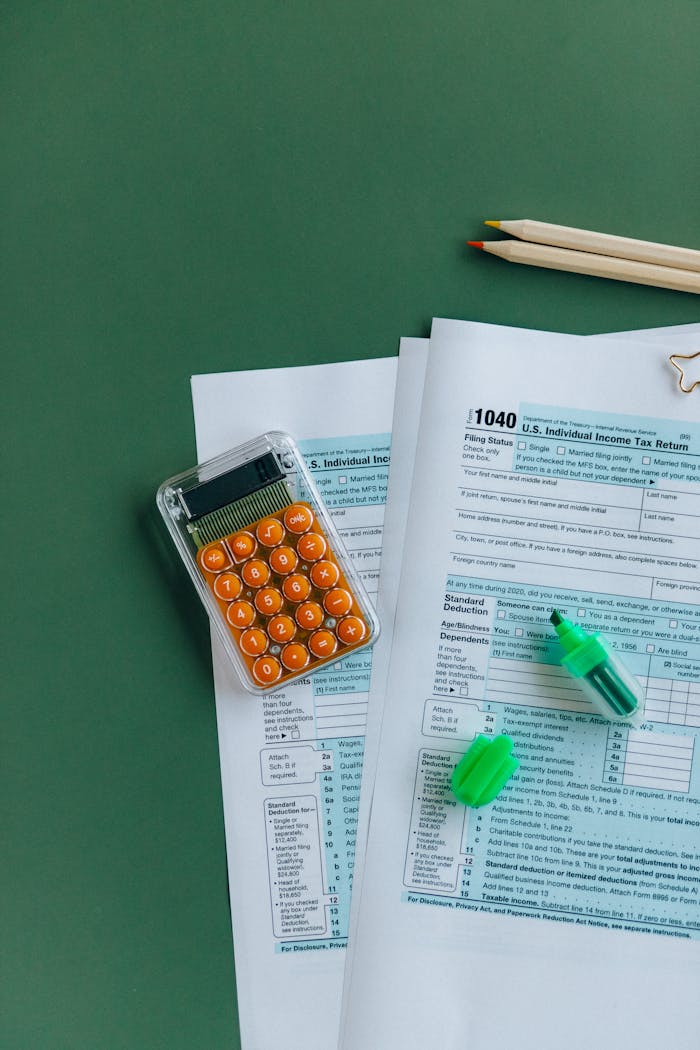 1040 tax forms with calculator, pencils, and markers on green surface.